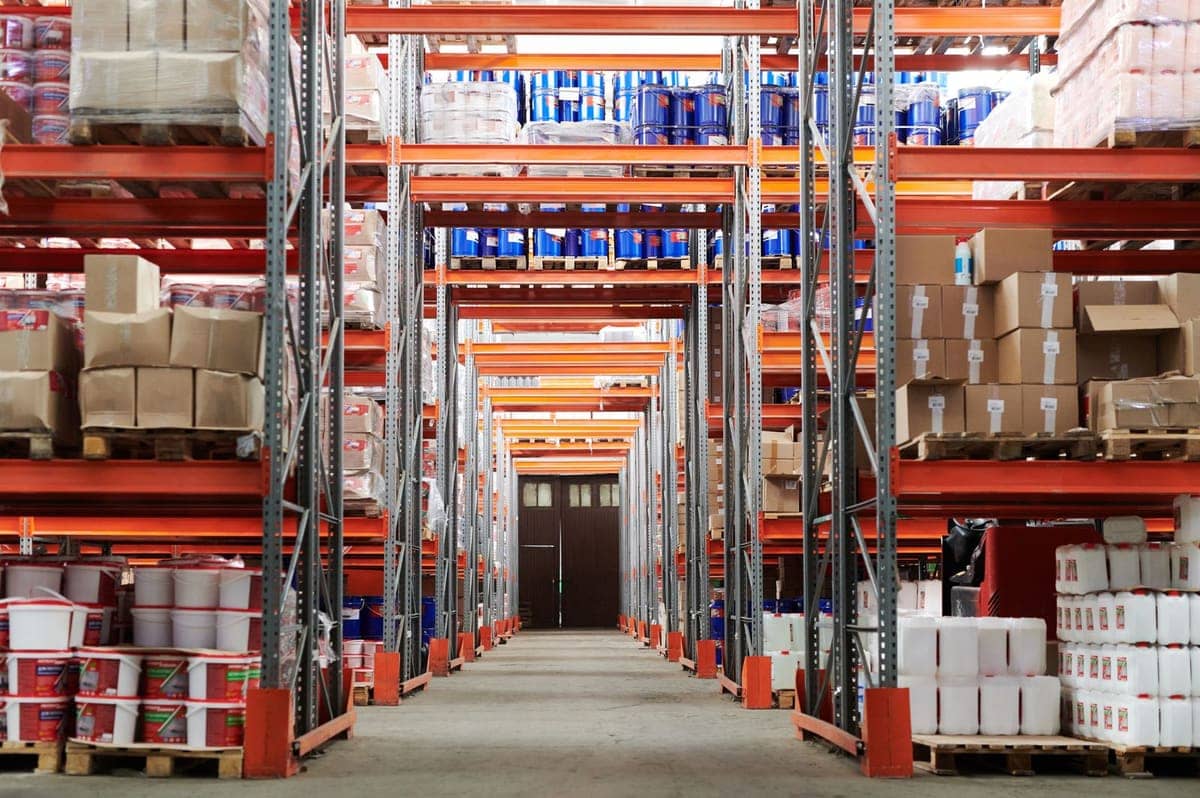 Pallet racking aisle in a bonded warehouse stacked with cartons and drums